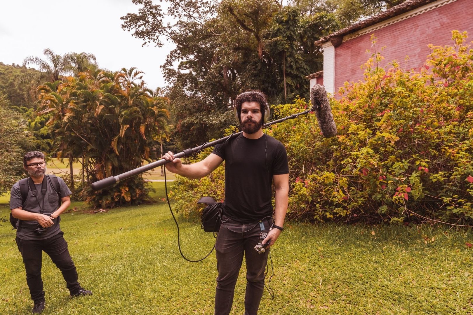 Sound technician holding a boom microphone in a lush tropical garden